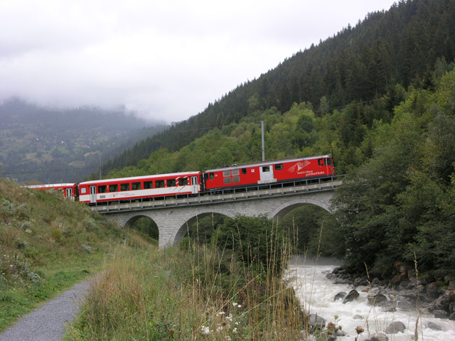 Na een poosje kondigt de Matterhorn-Gotthardbahn zich met een scherpe fluit vanuit de bossen boven ons aan.